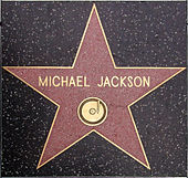 A pink star with a gold colored rim and the writing